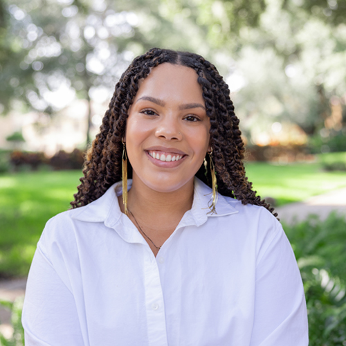 Staff Headshot – Woman in front of greenery outside